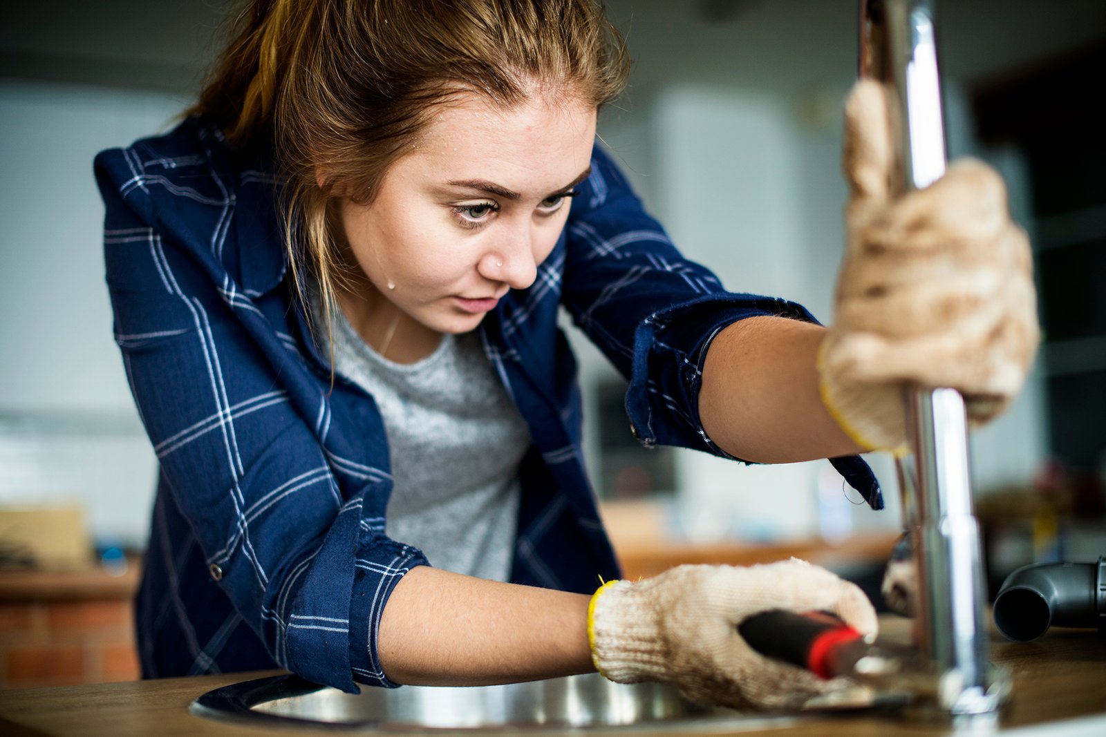 woman fixing kitchen sink