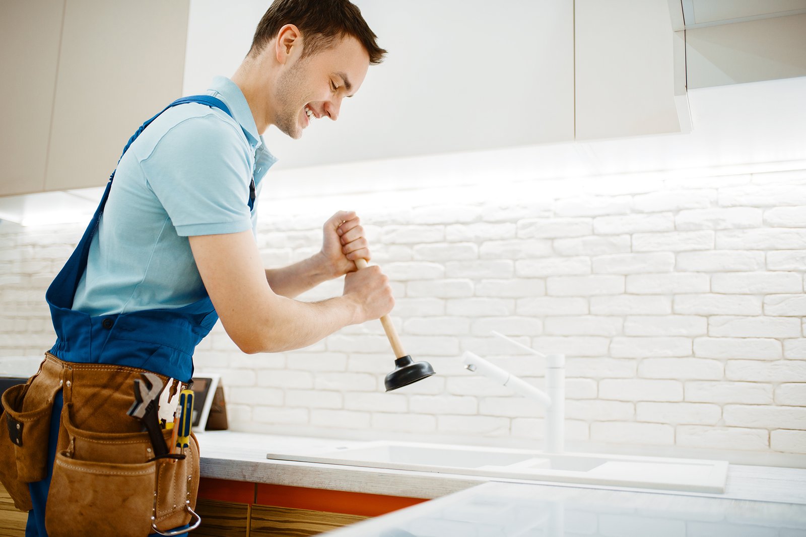 male plumber in uniform holds plunger, clog