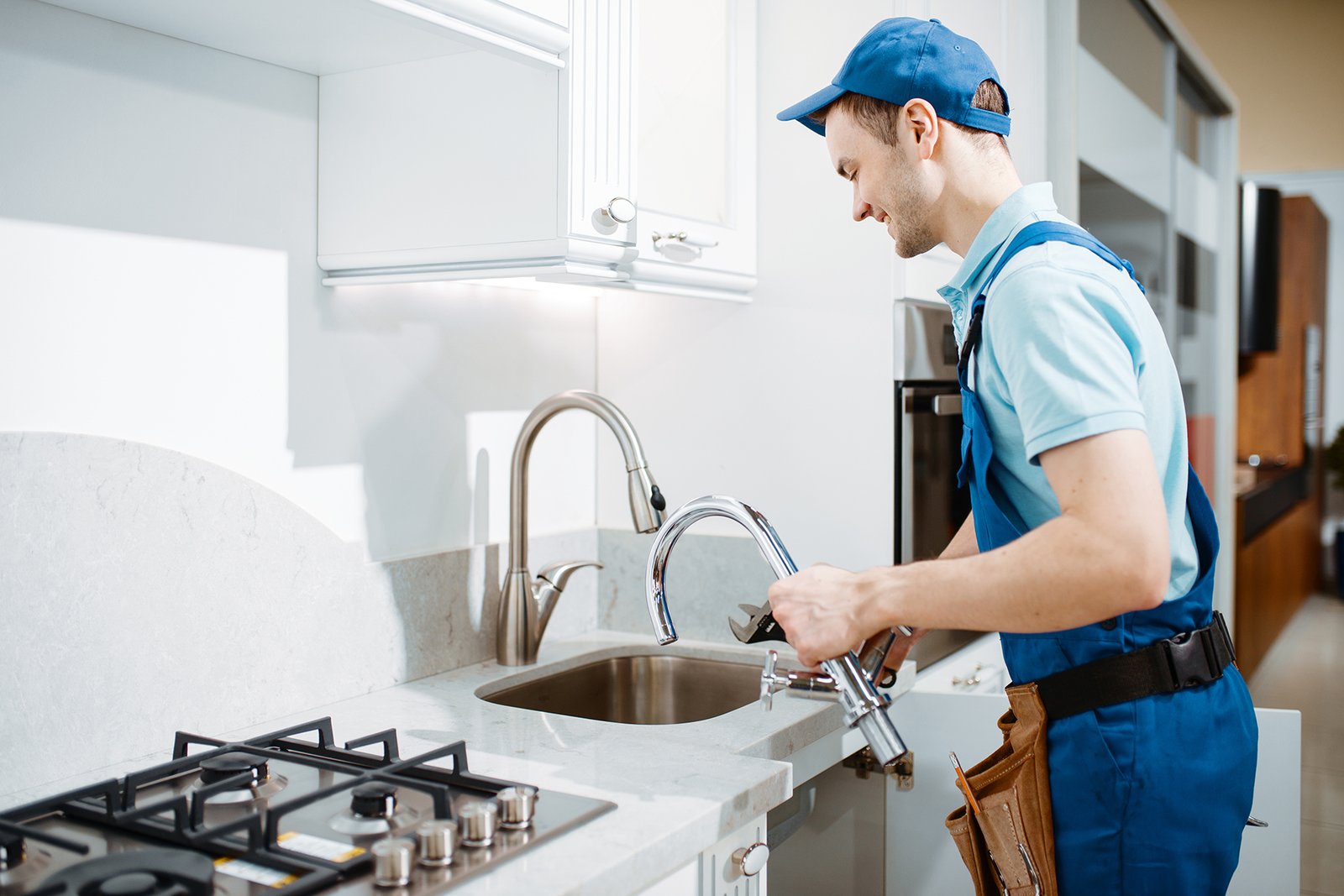 plumber in uniform changes faucet in the kitchen